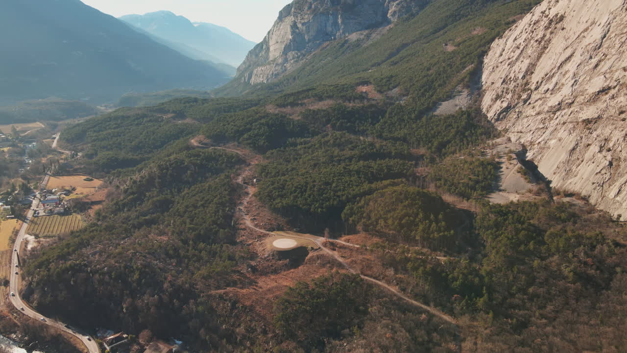 Volo sopra la campagna del Trentino con imponenti montagne rocciose in un soleggiato inverno in Italia
