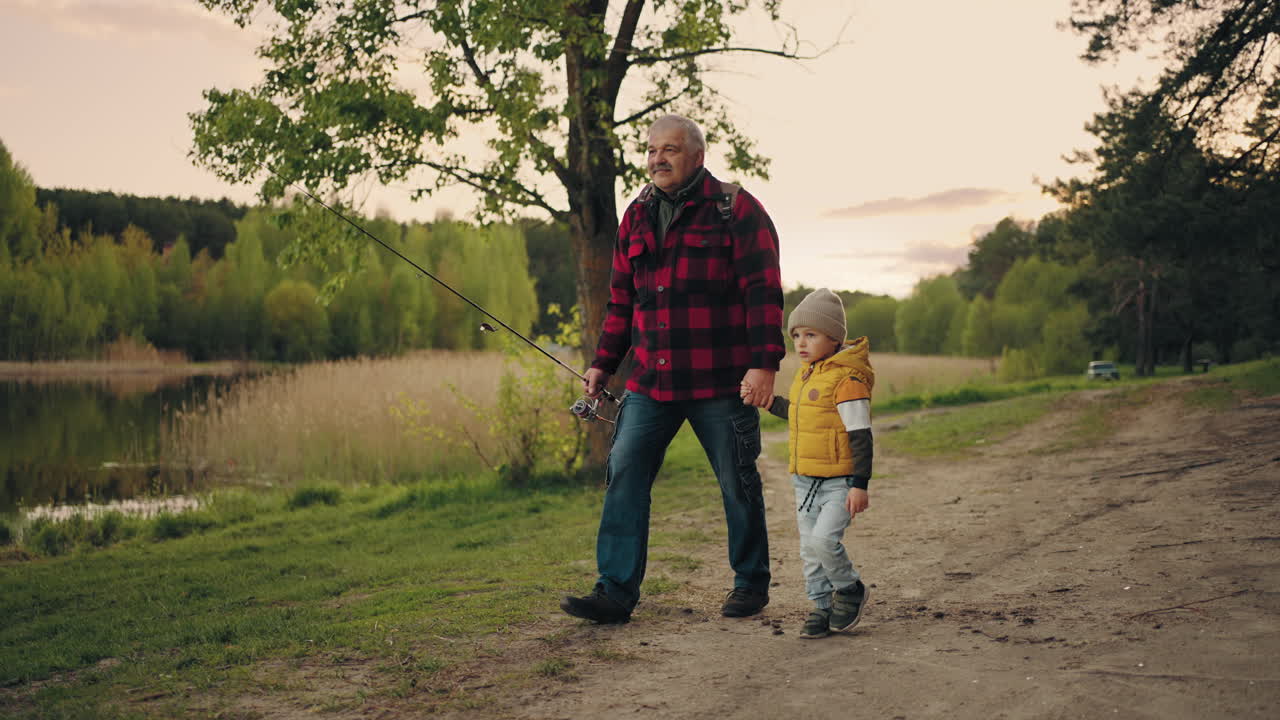 Gammel mand og barnebarn tilbringer tid sammen i naturen. Bedstefar og dreng ved søbredden.