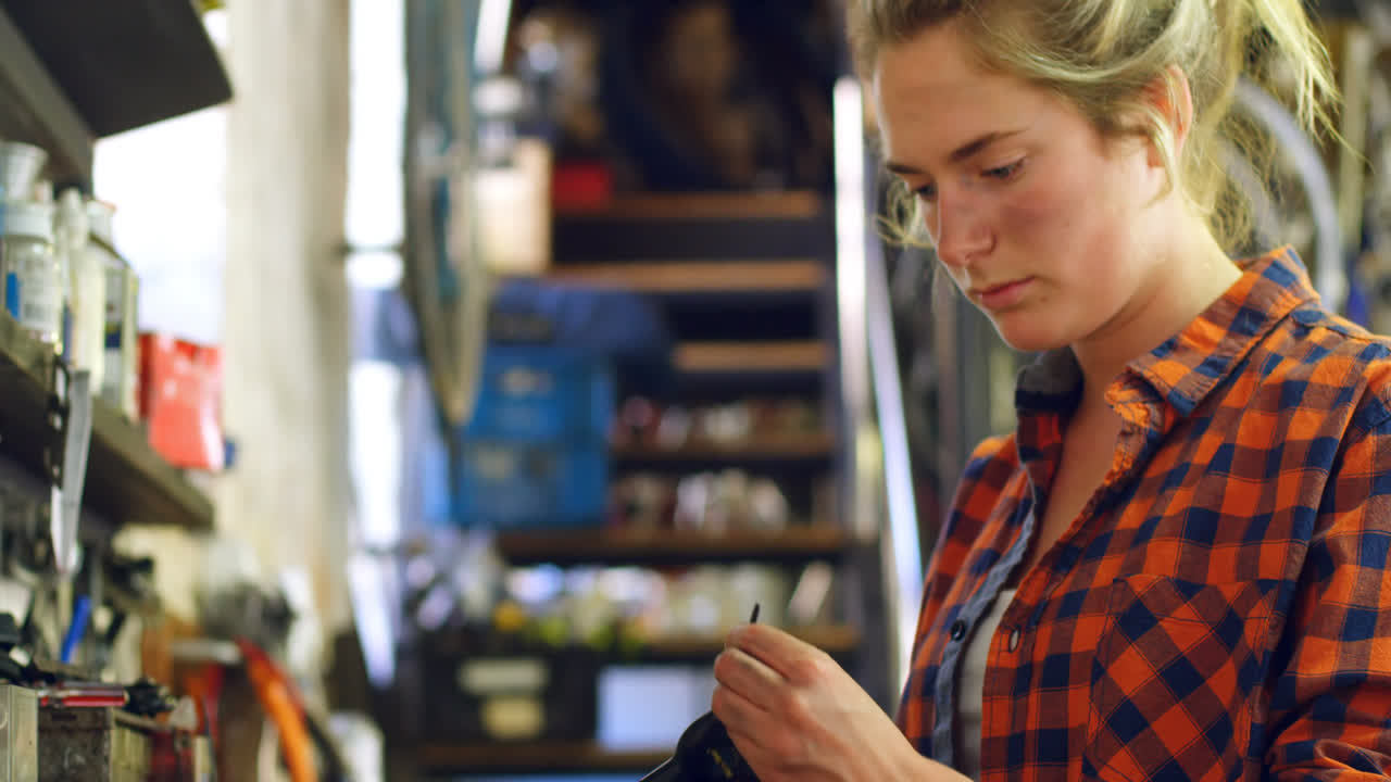 mujer ajustando una herramienta en el taller 4k