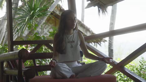 young woman meditating on the terrace of an exotic hotel in the tropics