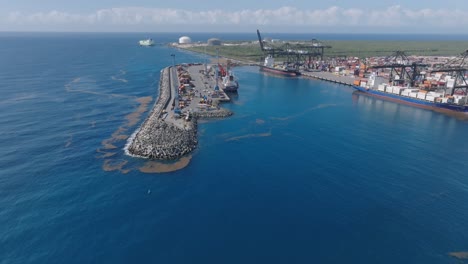 aerial forward over cargo harbor in the caribbean ocean, container and cranes