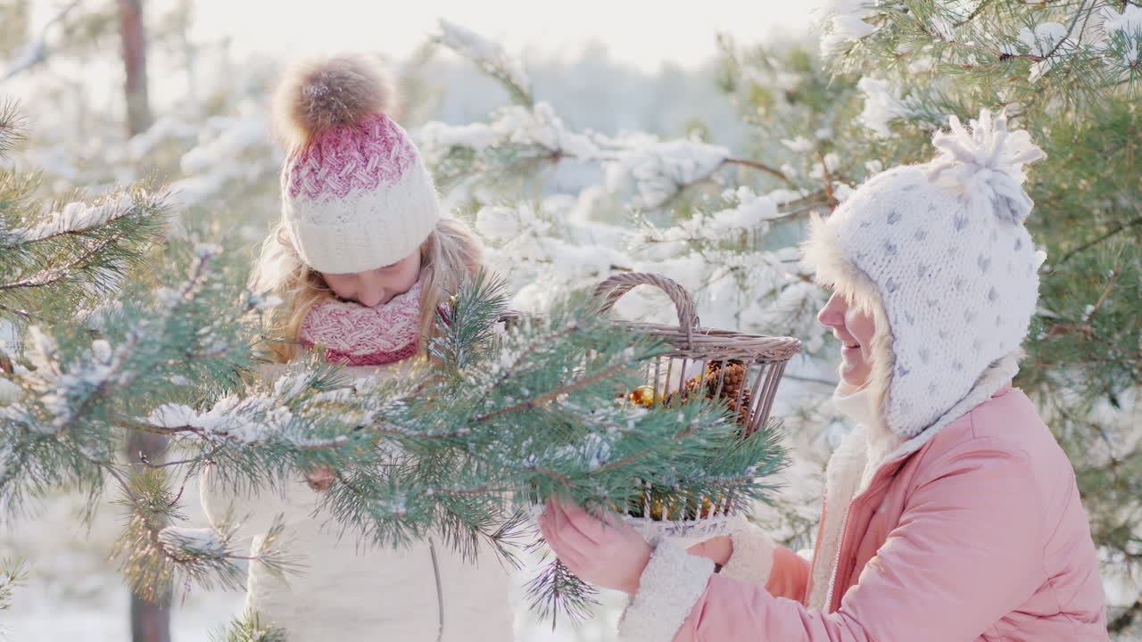 una niña y una madre joven decoran un árbol de navidad con bolas decorativas en la nieve