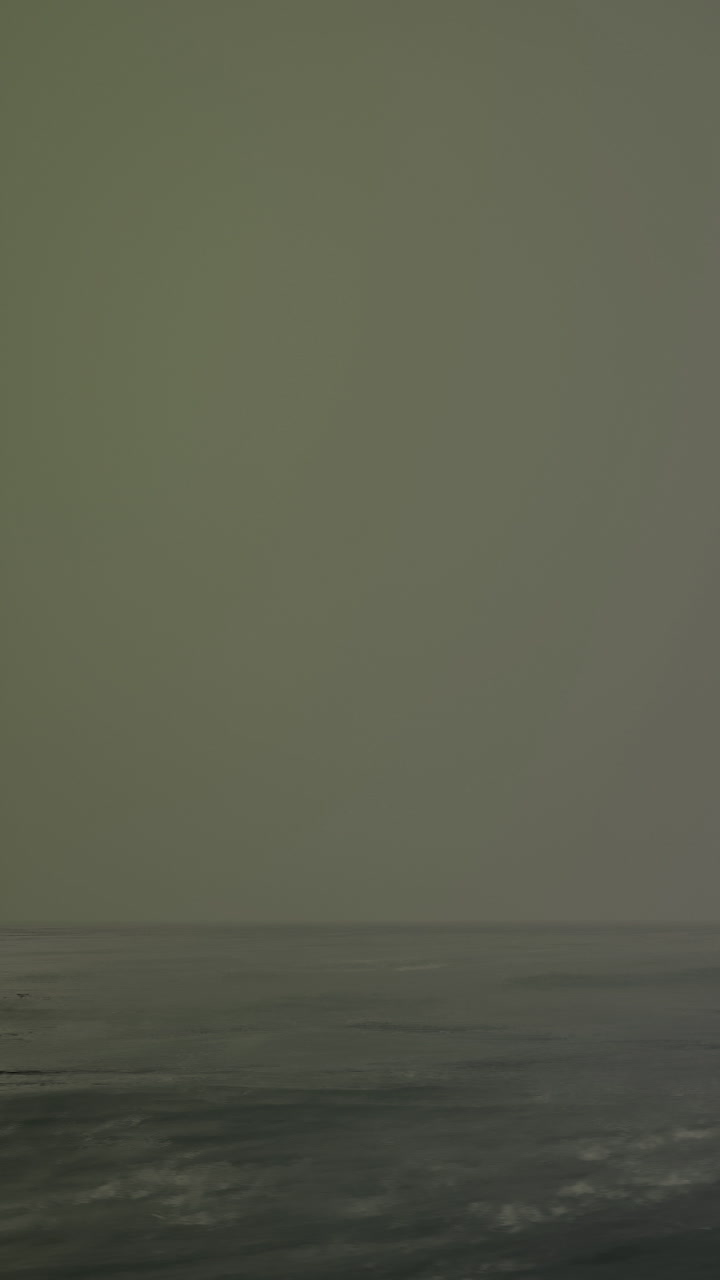 Waves crash on a quiet shore during early morning light on a misty day