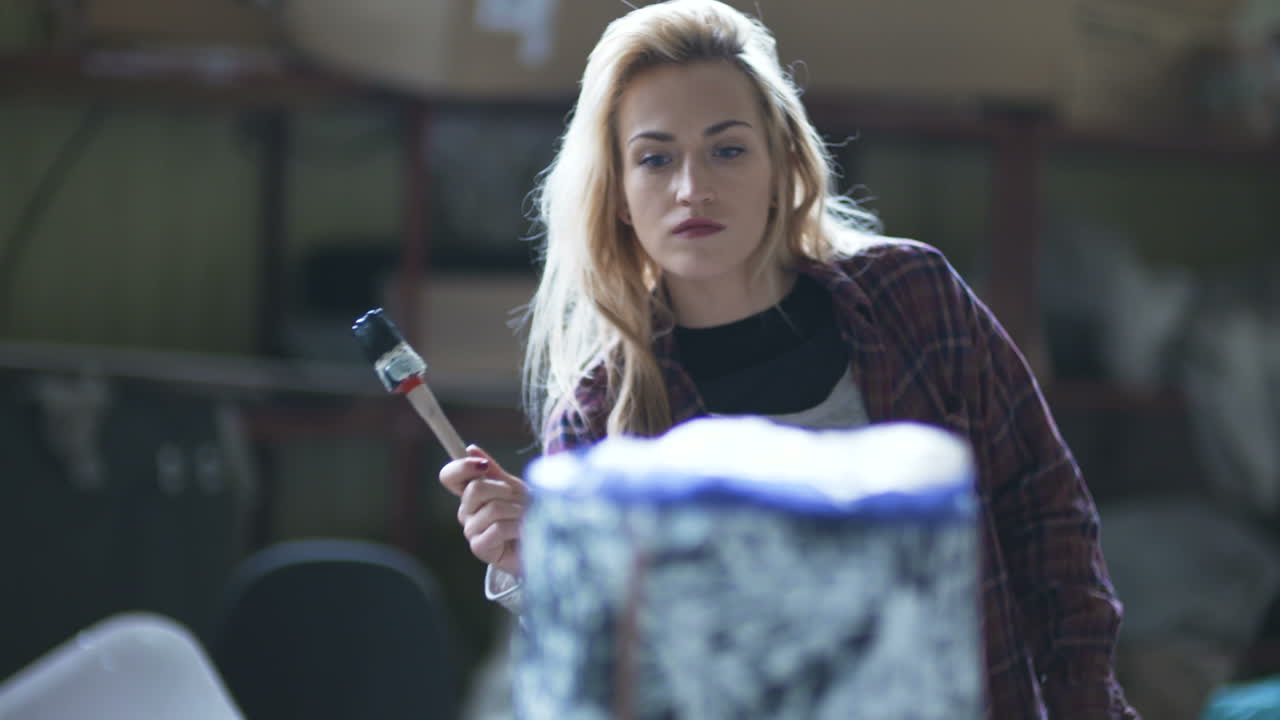 mujer rociando pintura en un tocón de árbol en el taller