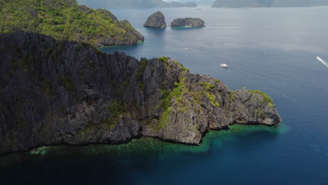 Cinematic-aerial-view-of-rugged-cliffs,-revealing-mountain-backdrop