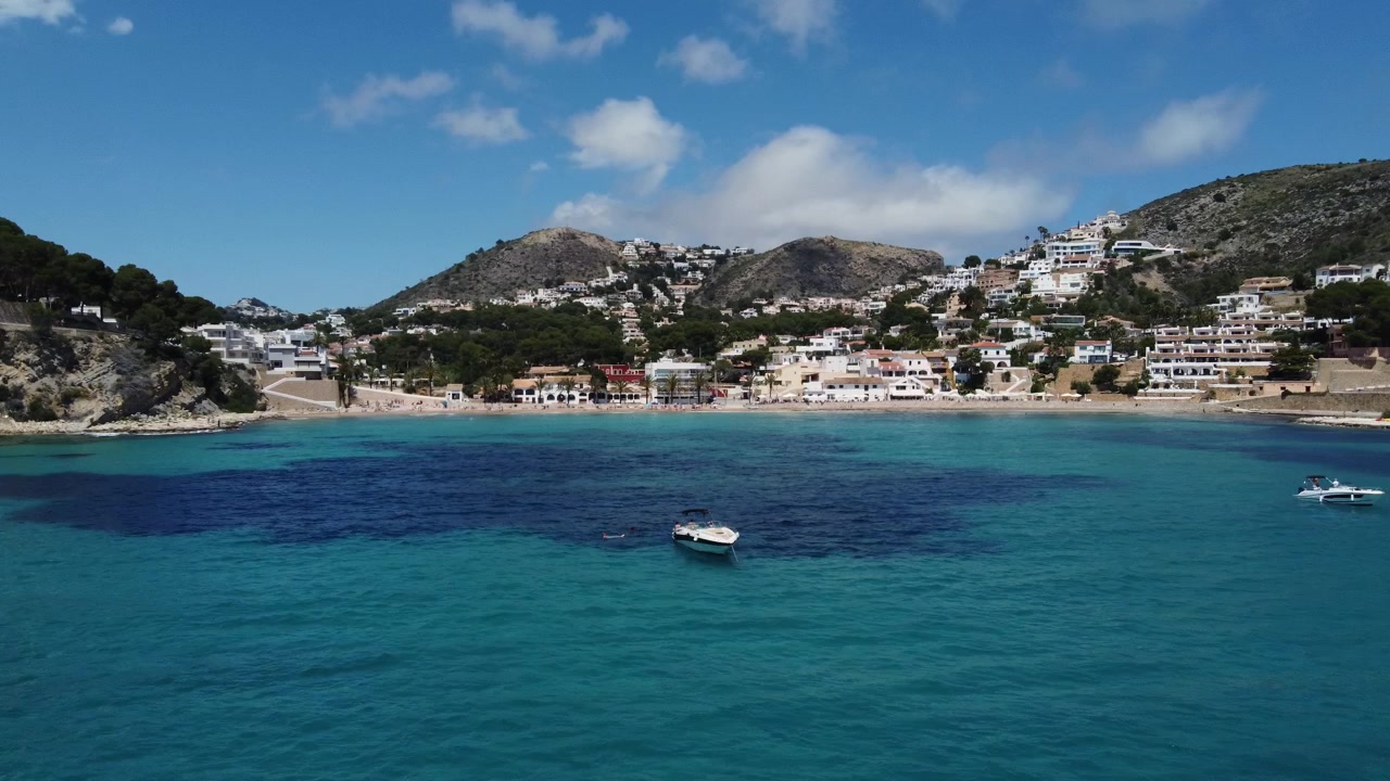 Splendida panoramica con drone di barche e yacht di lusso ancorati nelle acque turchesi della Baia di El Portet, una gemma mediterranea suggestiva a Moraira, Spagna.