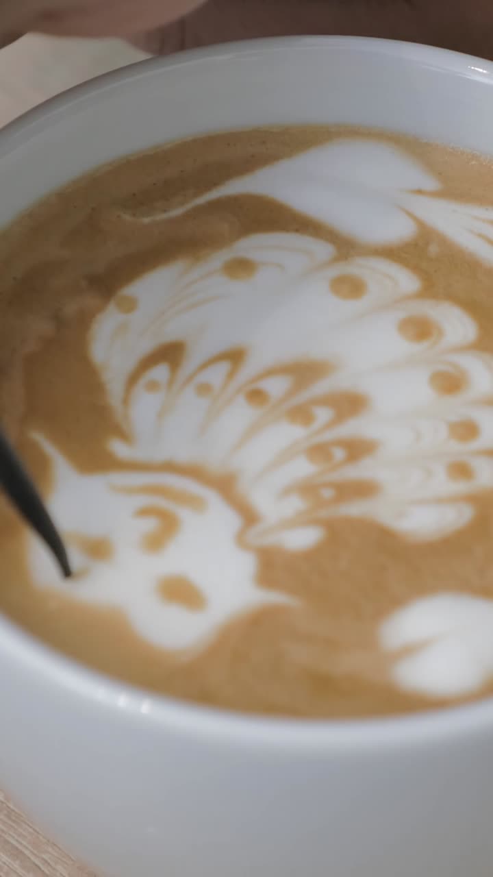Barista che crea dettagliata latte art a forma di pavone in una tazza di caffè