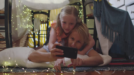 front view of caucasian woman using her phone with her daughter at home