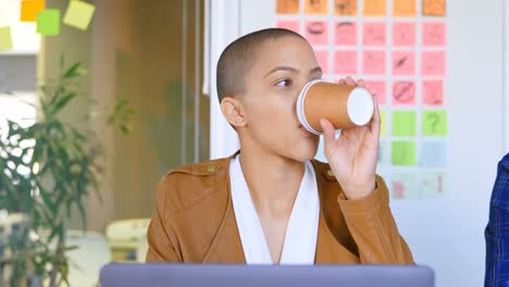 Front-view-of-young-caucasian-female-executive-having-coffee-at-desk-in-modern-office-4k