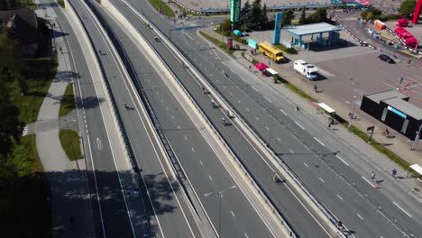 drone footage capturing the tallinn triathlon, showcasing cyclists on an elevated road, green landscapes, and urban surroundings on a clear day