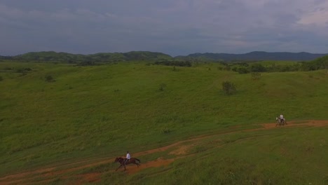 dos jinetes galopan sus caballos en un camino de tierra roja en una llanura venezolana, cámara lenta