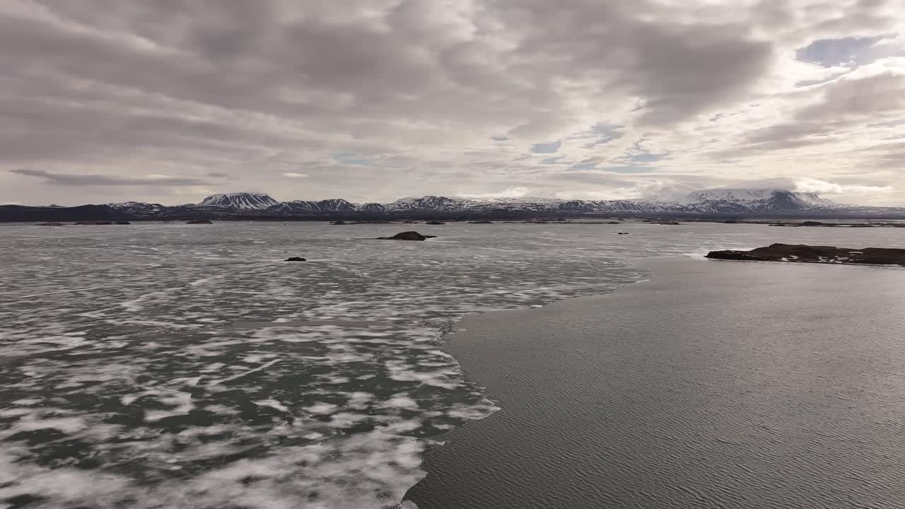 Sunset over Lake Myvatn with ice on the shore. Peaceful nature in Iceland with a view of the mountain range on the horizon