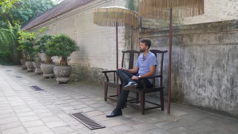 young handsome man finding time to relax on bench in public garden area