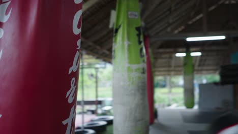 a man training muay thai in a gym with punching bags and a boxing ring