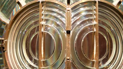 fresnel lens with brass structure, nautical lighthouse tower. detail of the glass lantern with rainbow spectrum. system of lamps and lenses to serve as a navigational aid. old sea searchlight beacon.