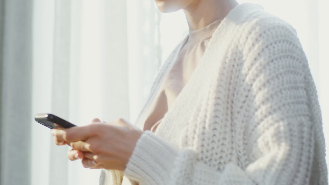 창문 근처에서 전화를 사용하는 여자