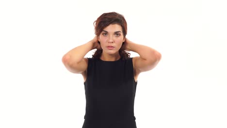 Attractive-young-woman-is-tiding-her-hair-looking-in-the-camera-like-in-the-mirror-and-asking-for-advice-standing-isolated-on-a-white-background.-Woman's-hairdo