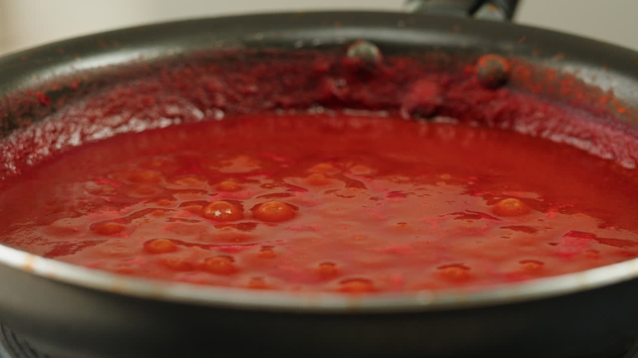 Chicken in tomato sauce is boiling on a frying pan with spices. Cooking tomato sauce curry with chicken fillet. Traditional Italian Mexican Asian dish. High quality studio shot for cafe, restaurant close up.