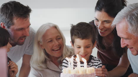 Familia-Multigeneracional-Celebrando-Su-Cumpleaños-Con-Su-Nieto-En-Casa-Mientras-Apaga-Velas