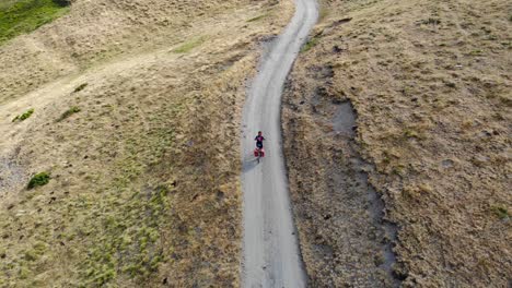aerial: mountain biker going downhill in a high mountain deserted area in summer time