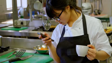 female chef using mobile phone while having coffee 4k