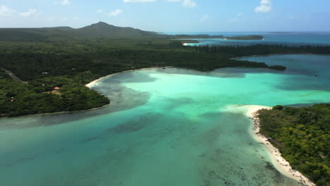 Shadows-from-clouds-over-the-crystal-waters-along-the-Isle-of-Pines,-New-Caledonia---Areial-flyover