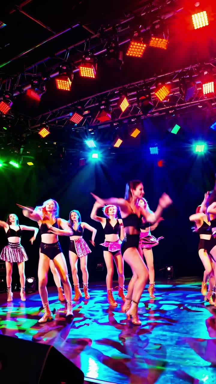Group of female dancers captivating audiences with modern dance choreography on stage, illuminated by vibrant LED lights and a dynamic LED screen reflecting their energetic movements