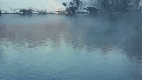 mist over river in winter forest. fog over winter river. river in winter park