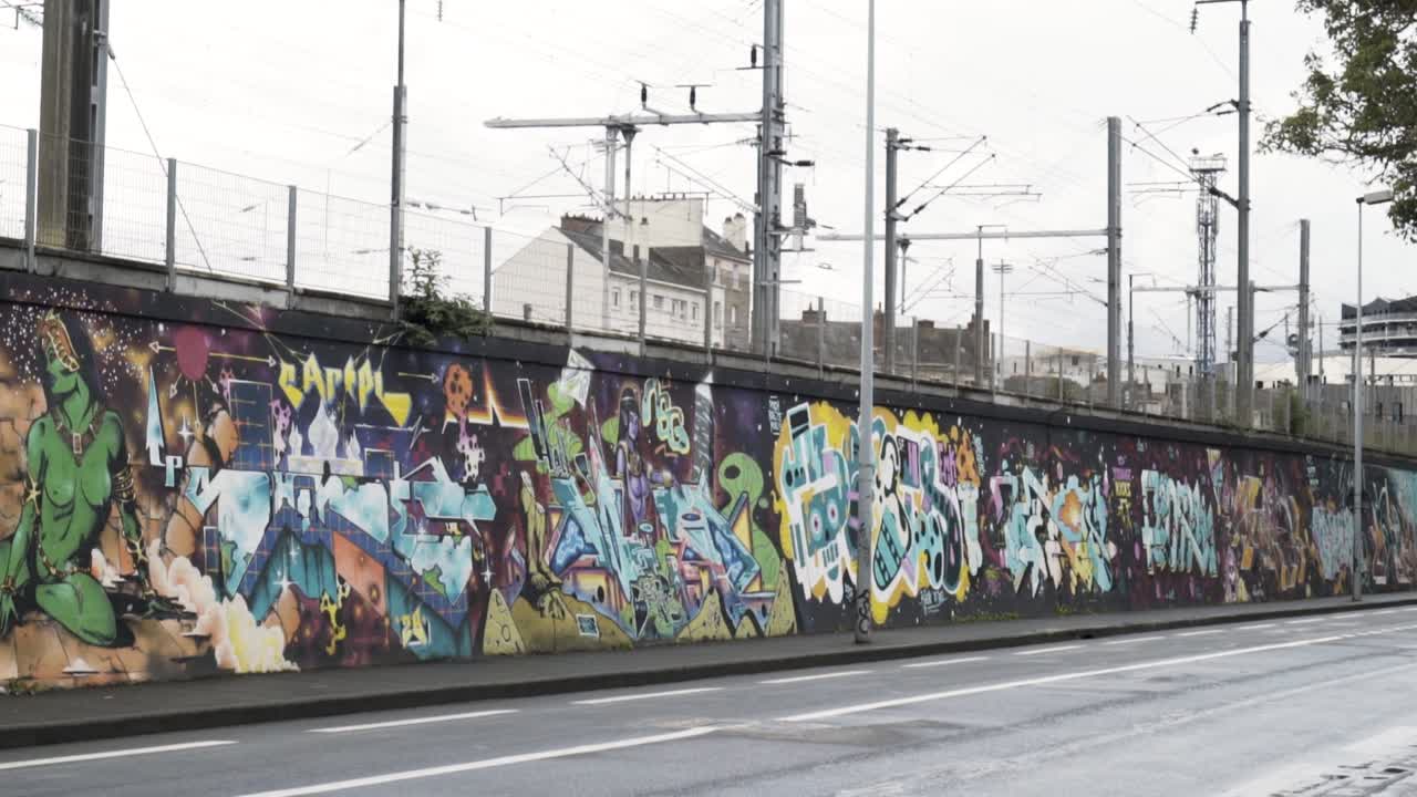 Muro coperto di graffiti lungo una strada cittadina