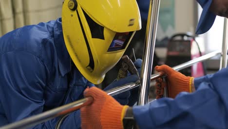 closeup of man wearing mask welding in a workshop. metal workers use manual labor. skilled welder. welder is welding the stainless steel pipes in the factory. welder industrial automotive part in factory.