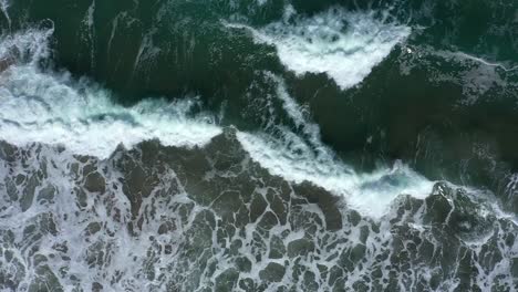 top down drone shot of west coast waves crashing on a rocky shore