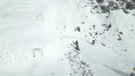 Aerial-drone-bird's-eye-view-over-people-going-up-the-mountain-by-chairlift-at-Engelberg-Brunni-bahnen-along-the-Swiss-alps-in-Switzerland-on-a-sunny-day