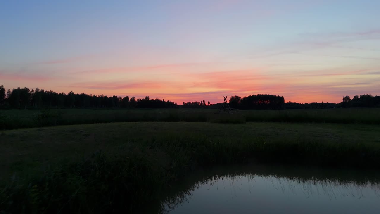 Drone Ascending Over Misty Pond at Sunset Aerial View Revealing Meadow and Golden Horizon in Tranquil Latvian Countryside