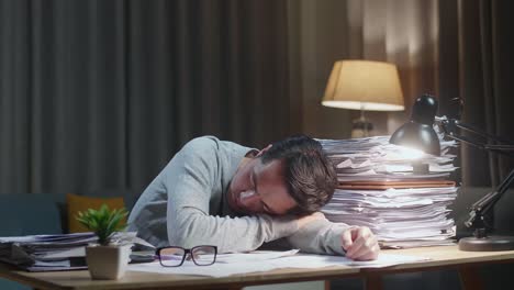 tired asian man sleeping due to working hard with documents at home