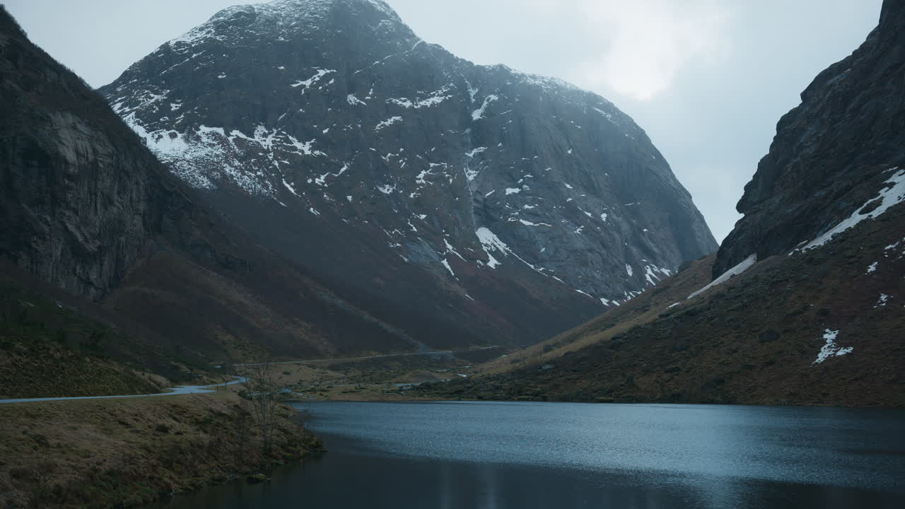 Bredt billede af en naturskøn dal i Norge med høje bjerge og stejle klipper og en sø i midten