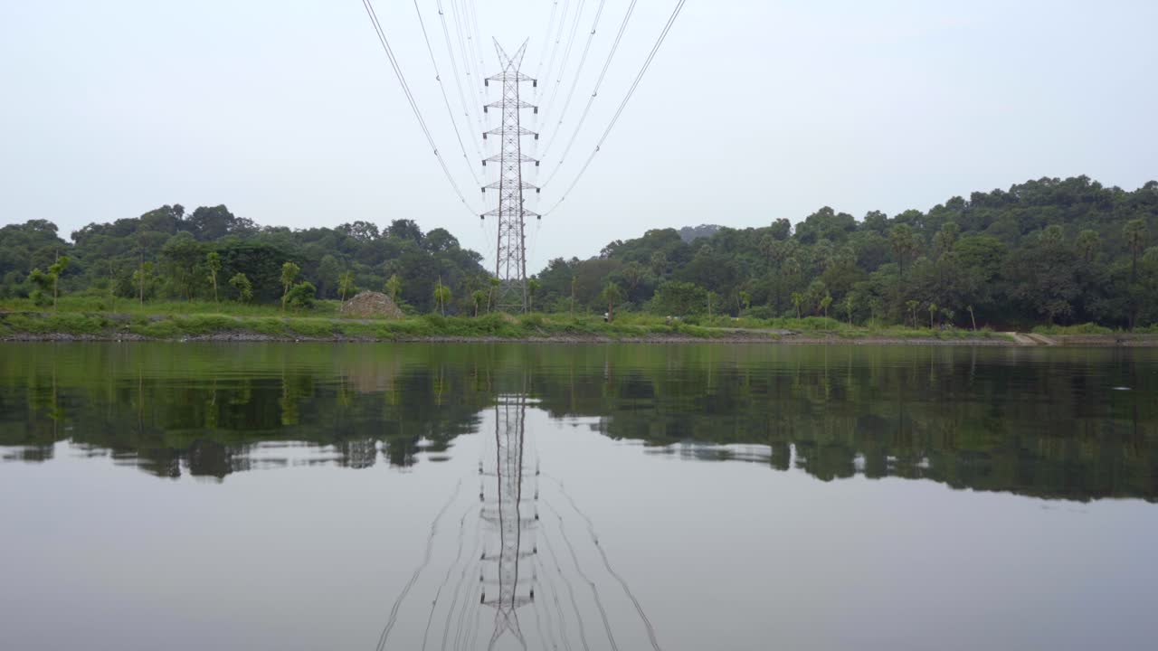 torre de transmisión red eléctrica línea eléctrica junto al lago sobre el reflejo de la montaña en el agua como un espejo