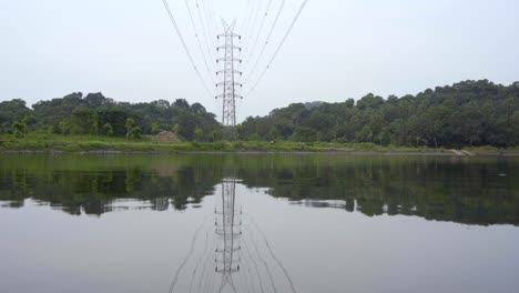 transmission tower power grid power line by the lake over the mountain reflection in water like a mirror