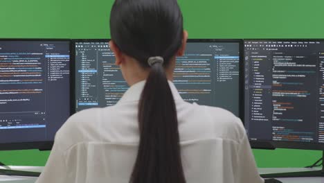 woman programmer coding on multiple monitors