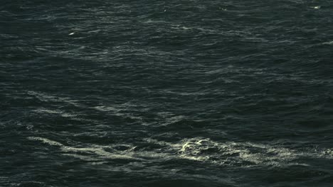 cinematic aerial shot of dark ocean surface, moody sea waves