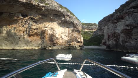acercándose a una zona de baño protegida y una playa en la costa de hvar, croacia, con escarpados acantilados de piedra caliza y pequeños hinchables