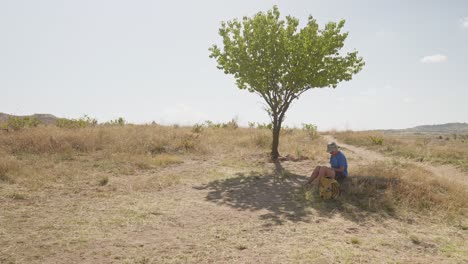 female hiker rests in shade of lone tree hot day cappadoccia turkey