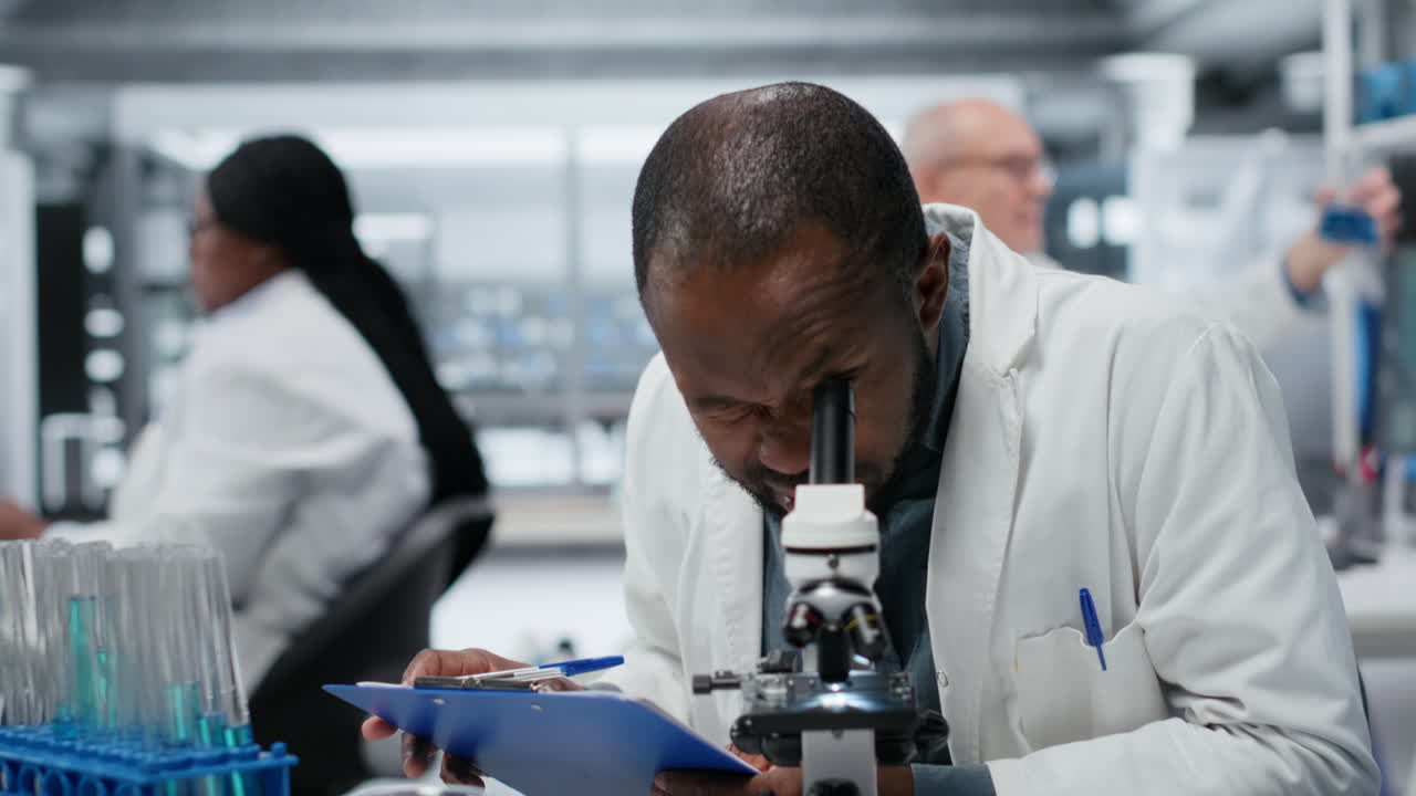Male cytotechnologist using optical microscope to study microorganisms