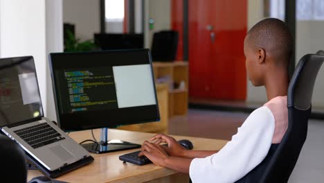 Side-view-of-young-black-businesswoman-working-and-sitting-at-desk-in-a-modern-office-4k