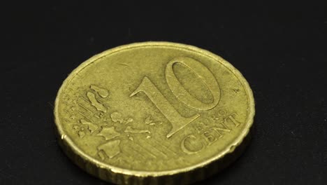 golden ten cents coin rotating on a black surface, macro shot in 4k extreme detail close up view