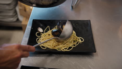 chef plating a gourmet dish of spaghetti with mussels