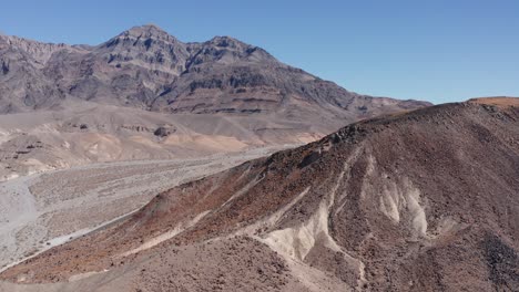 aerial low shot flying over a rocky ridge in the desert landscape of death valley, california. 4k