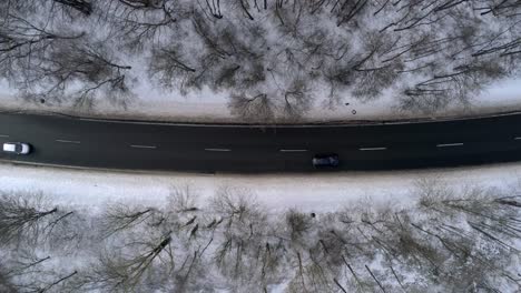 birdseye aerial view of cars on wet road and snowy countryside landscape