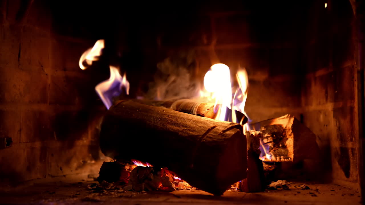 Warmth and comfort at home in cold season. Fire and smoke over wooden logs in fireplace. Wood burning in a stone fireplace. Close-up.