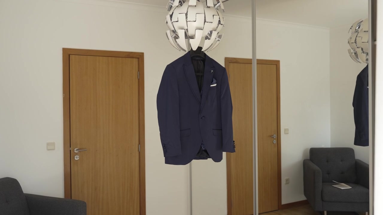 Completo blu navy formale appeso in una stanza moderna con arredamento minimalista e porte in legno
