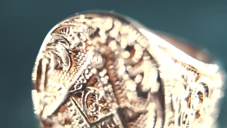 a macro detailed shot of a golden textured freemasons ring, on a rotating stand, mirror reflection, illuminati symbol, professional studio lighting, 4k video